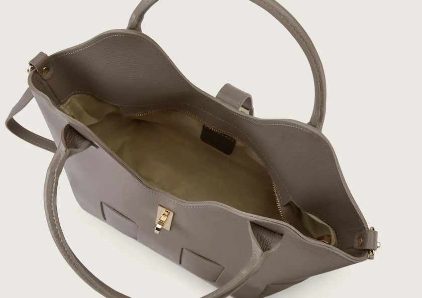 Close-up of the grey leather handbag featuring a secure top zip closure with metal detailing.